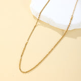 Gold chain necklace on a beige surface with a white cloth